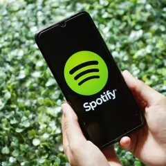 Ręce trzymają smartfon z logo Spotify. Skorzystaj z promocji spotify 3 miesiące za darmo i słuchaj ulubionej muzyki.