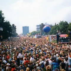 Tłum ludzi na ulicy podczas Love Parade Berlin. Wielki niebieski balon unosi się nad głowami.