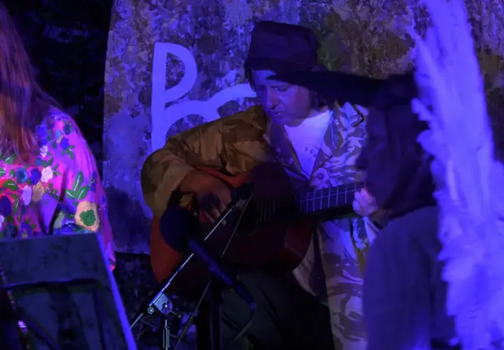 Muzyk gra na gitarze, a wokalistka śpiewa. Atmosfera sugeruje starorzymską pieśń żałobną.