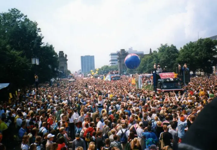 Tłum ludzi na ulicy podczas Love Parade Berlin. Wielki niebieski balon unosi się nad głowami.