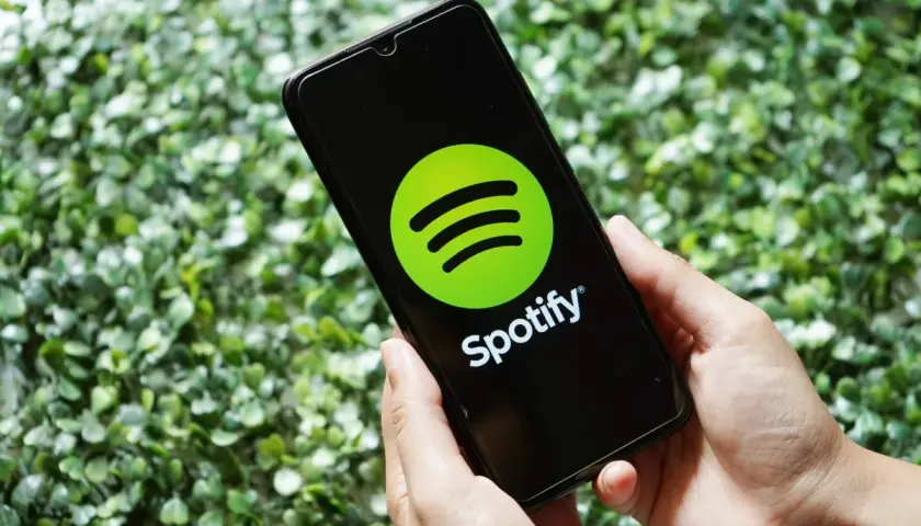 Ręce trzymają smartfon z logo Spotify. Skorzystaj z promocji spotify 3 miesiące za darmo i słuchaj ulubionej muzyki.