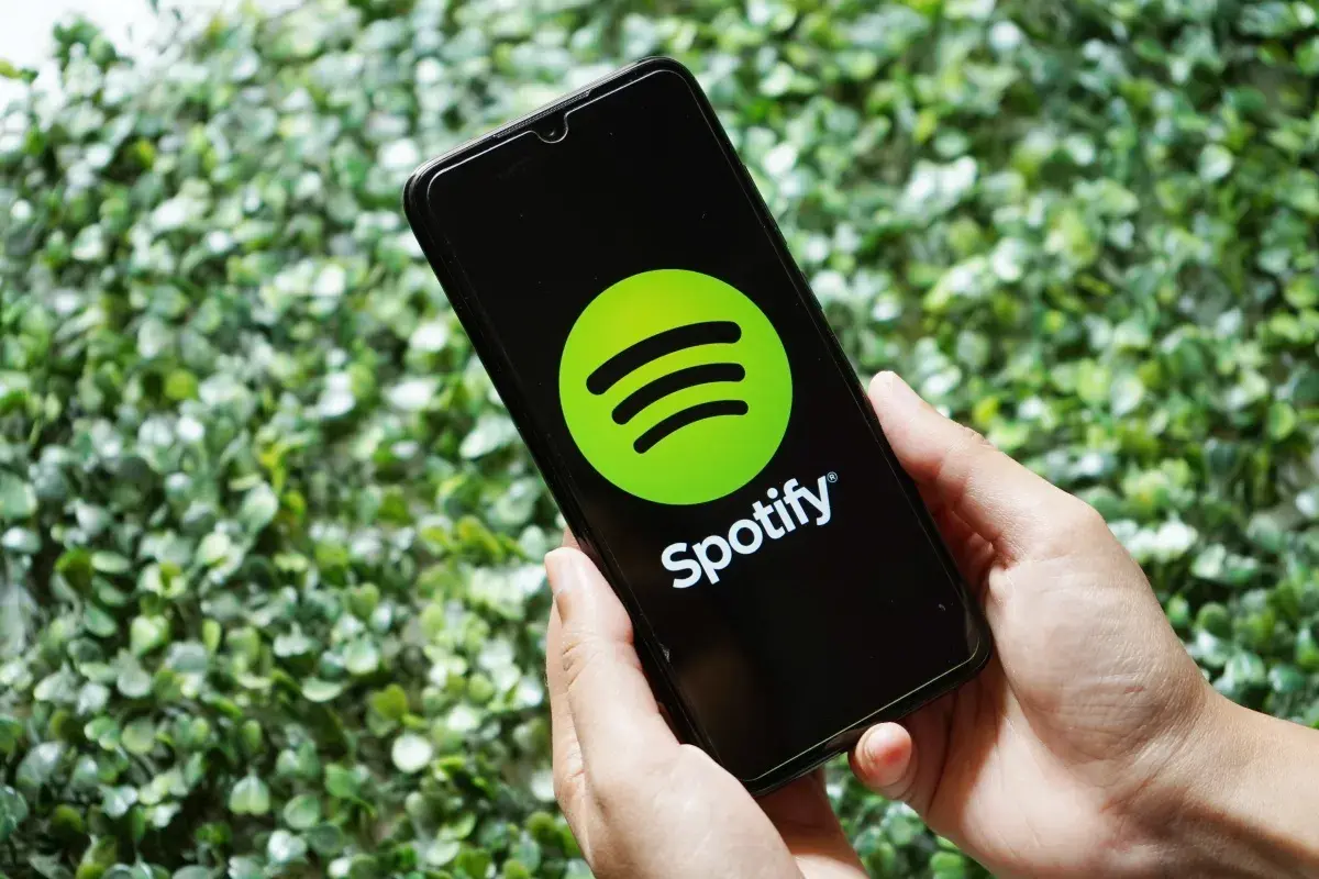 Ręce trzymają smartfon z logo Spotify. Skorzystaj z promocji spotify 3 miesiące za darmo i słuchaj ulubionej muzyki.