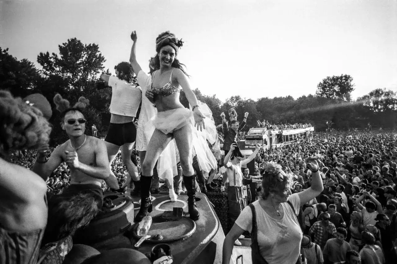 Tłum ludzi na Love Parade Berlin. Ludzie tańczą na platformach, świętując radość i wolność.